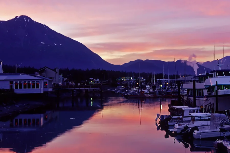 marina at sunset. mountains in background. several yachts and smaller dingys on the water