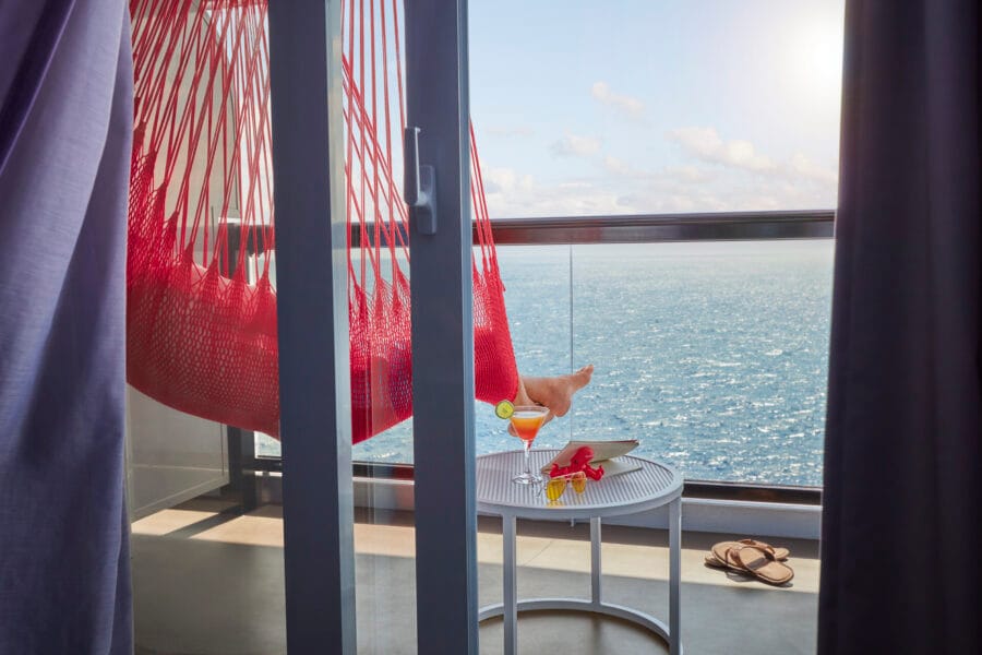 virgin voyages cruises signature red hammock hanging from a cabin balcony